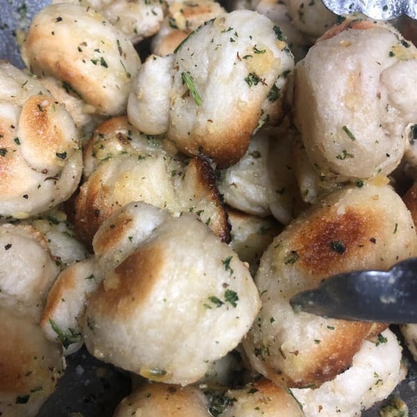 Close-up of golden-brown garlic knots with green herbs, ready to be served at Lyndhurst Pizza.