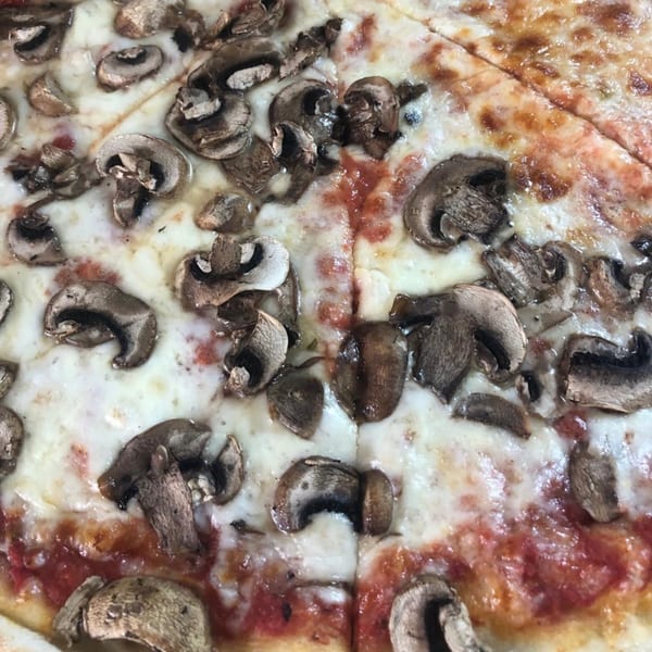 Close-up of a Lyndhurst Pizza mushroom pizza, with melted cheese and tomato sauce visible.