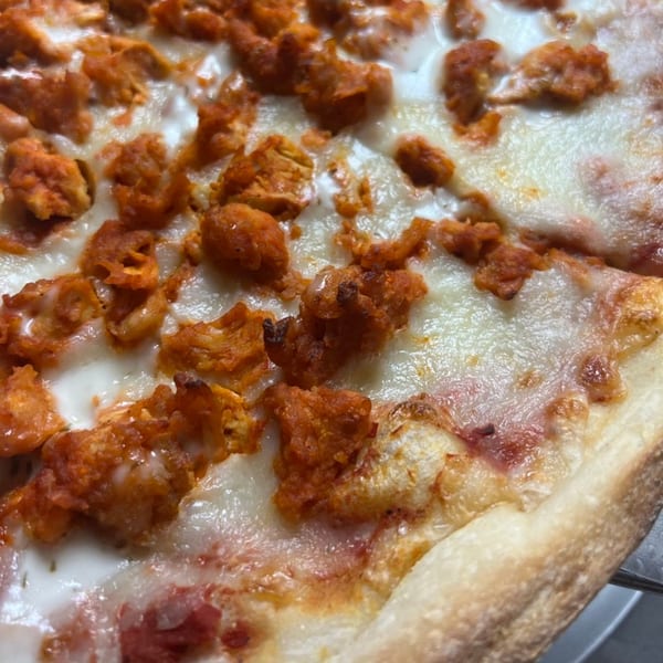 Close-up of a Lyndhurst Pizza buffalo chicken pizza with melted mozzarella and spicy chicken pieces.
